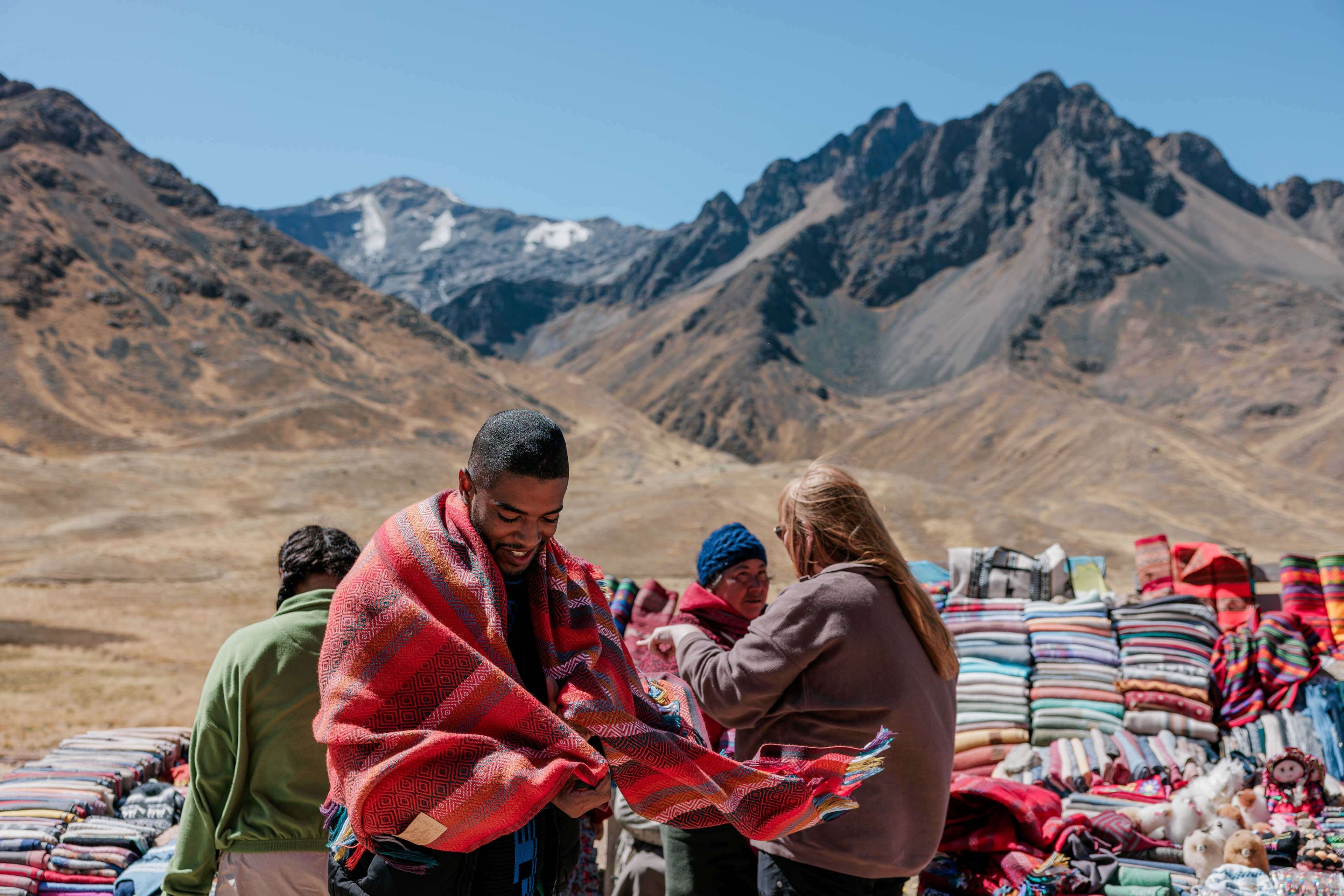 Person Wearing A Poncho Local Sellers Showing Their Different Ponchos As Background