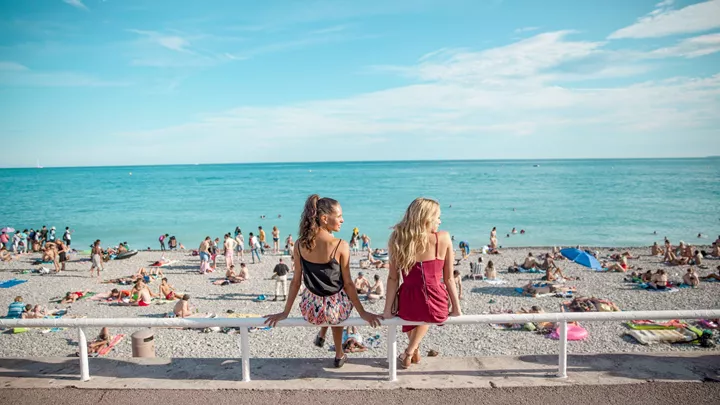 Travellers sitting on the promenade in front of the beachfront in the French Riviera, France