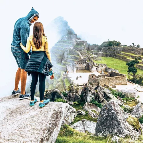 Machu Picchu emerges through the clouds as Contiki travellers admire Peru's iconic Inca citadel on Contiki's Lima to La Paz Tour