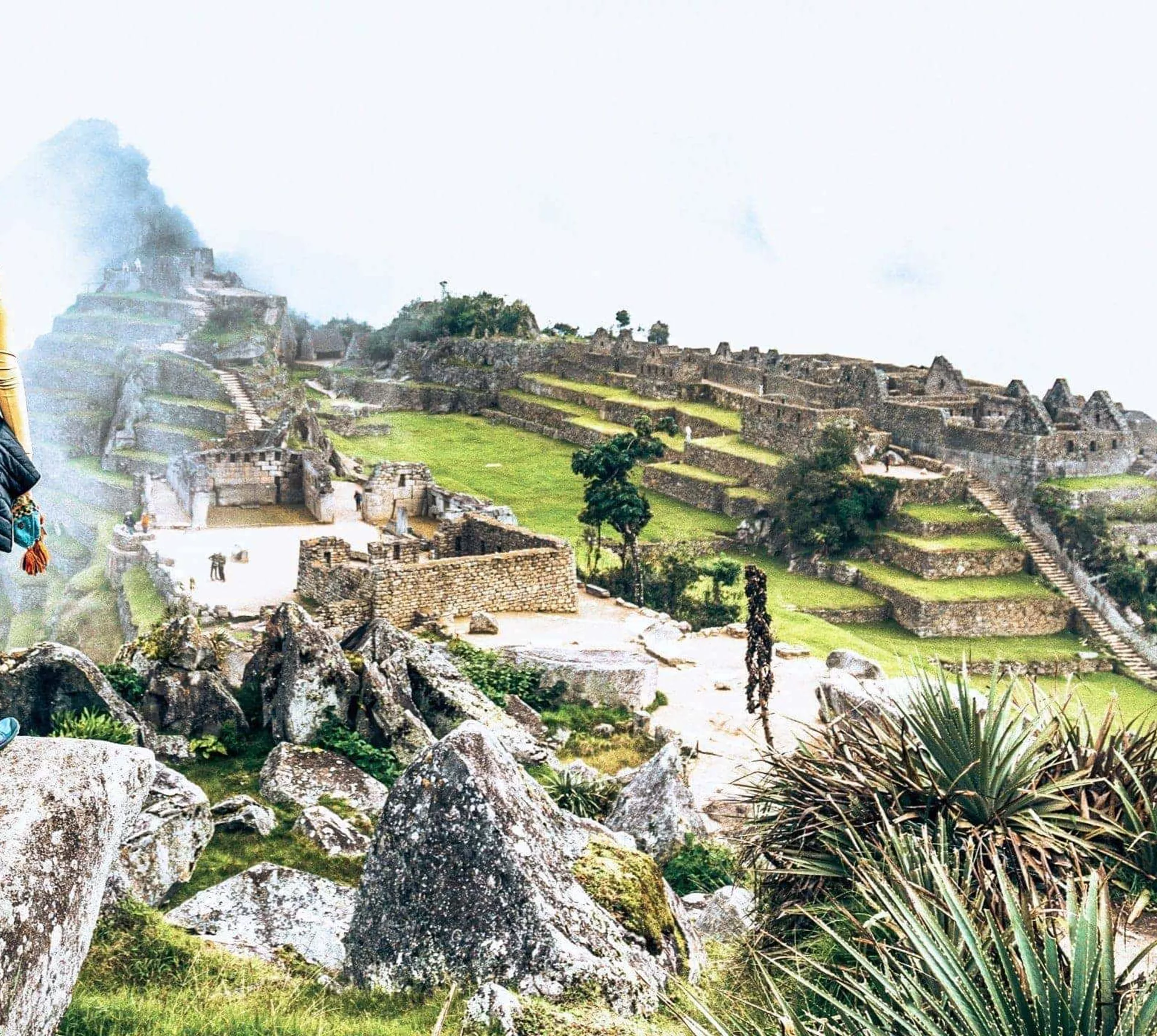 Machu Picchu emerges through the clouds as Contiki travellers admire Peru's iconic Inca citadel on Contiki's Lima to La Paz Tour