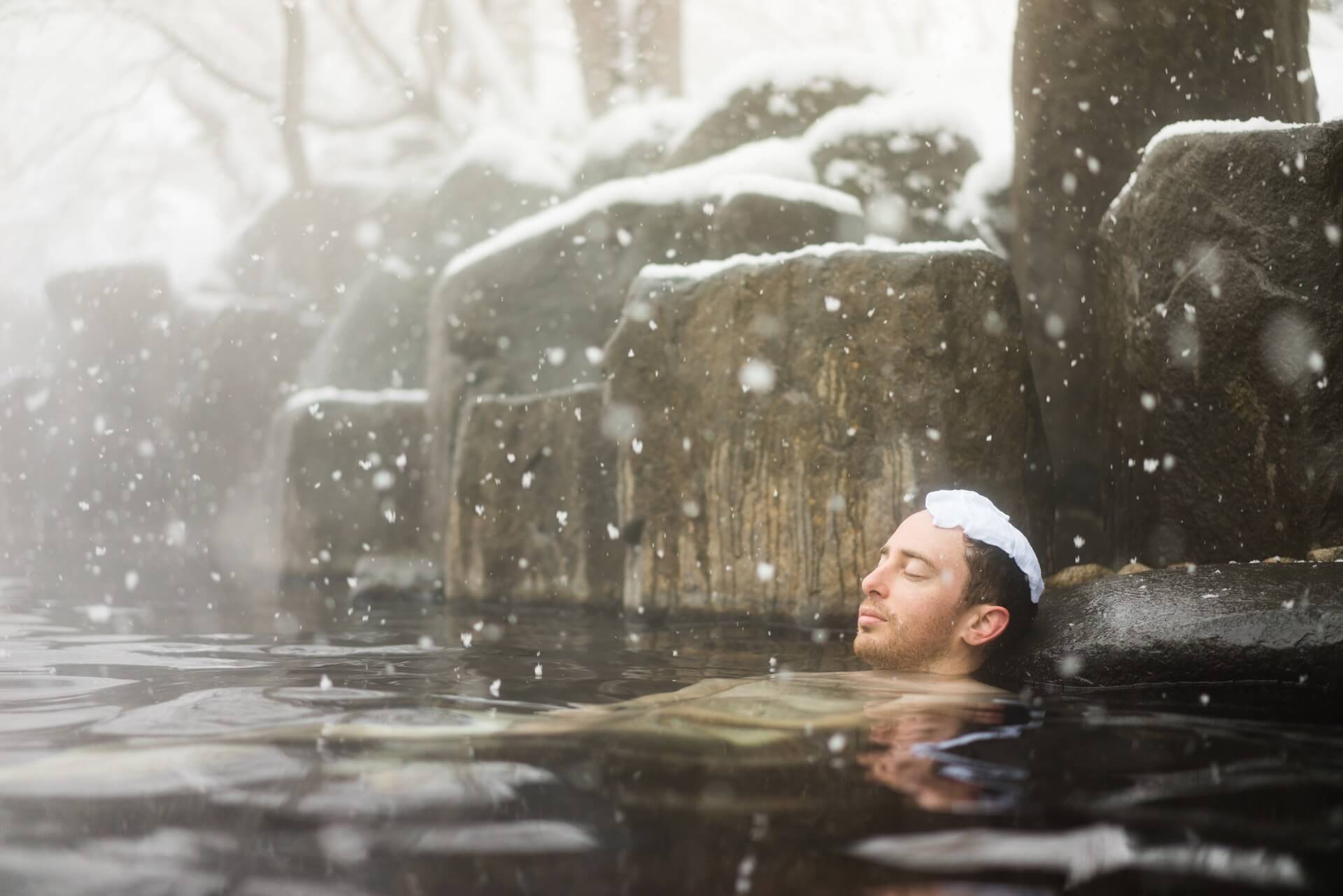 Western tourist enjoying natural Hot Spring Onsen during winter