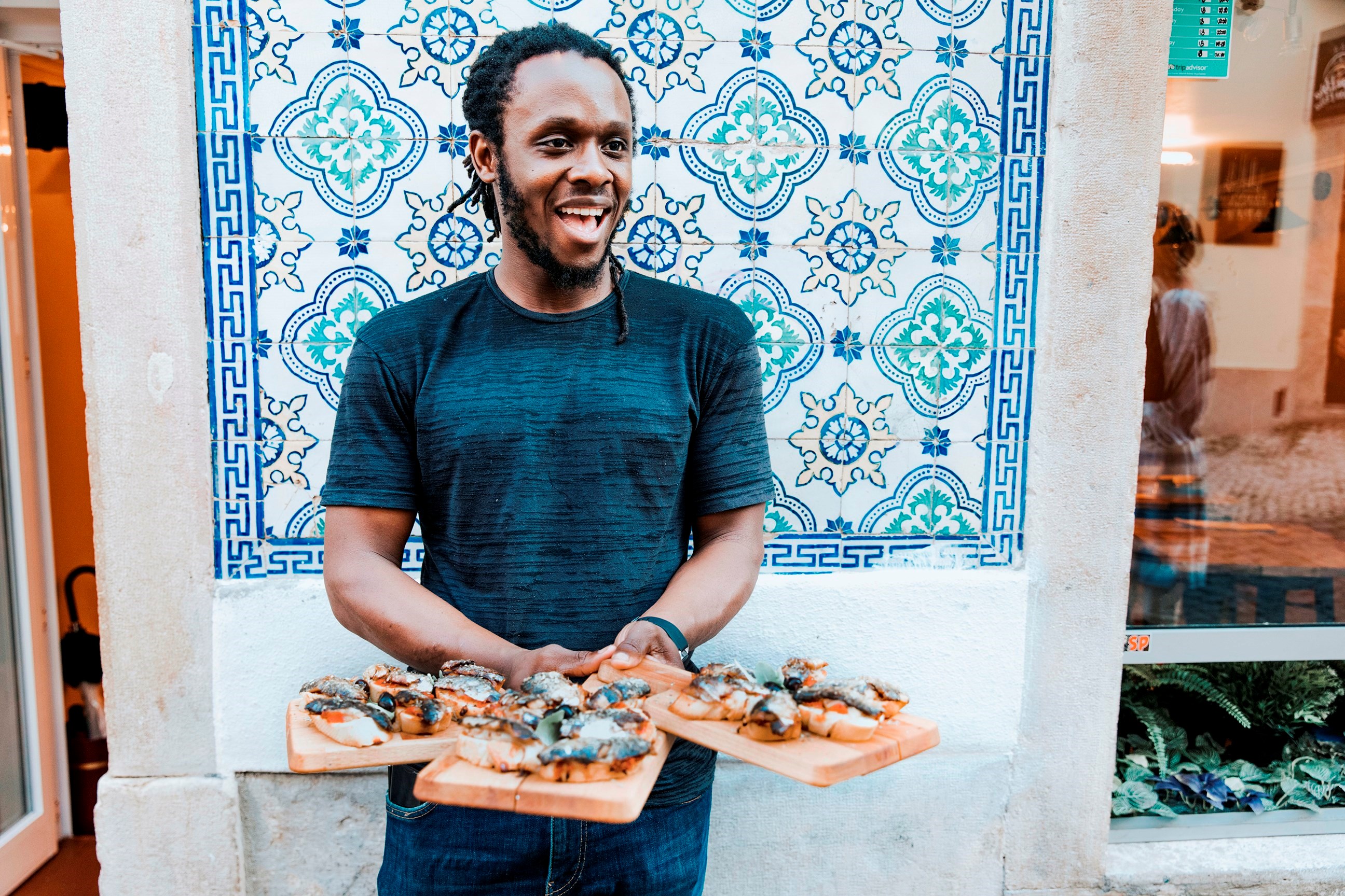 Man Holding Wooden Boards of Food outside Tiled Wall of Restaurant, Porto, Portugal