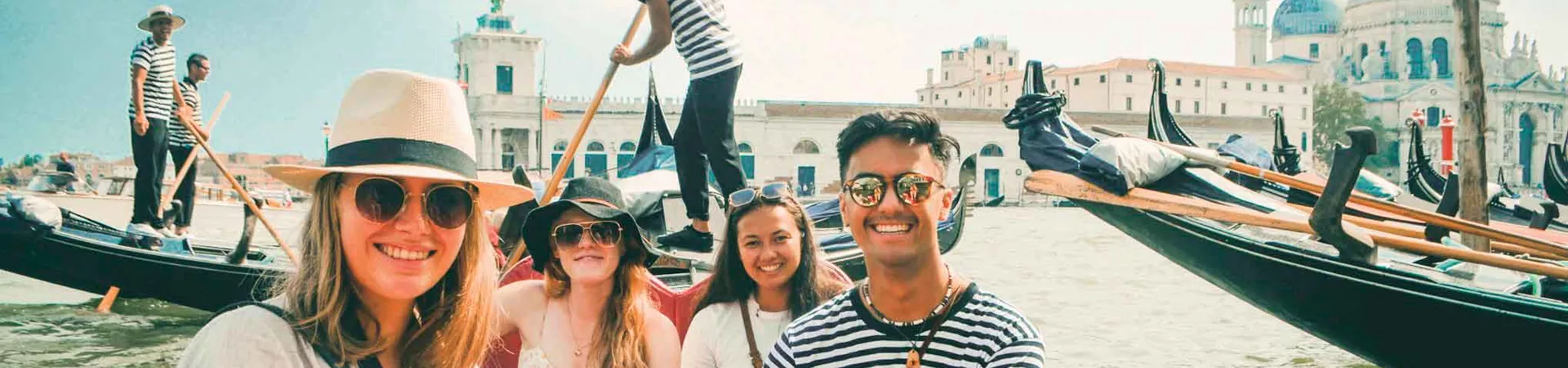 Group Of Youg Travelers On Gondolo In Venice Italy