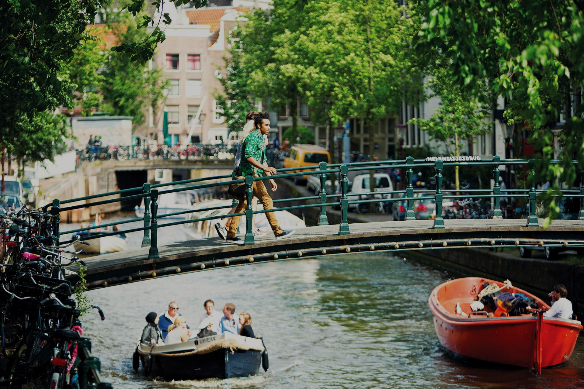Boats on city canal and people on the bridge in Amsterdam, Netherlands 