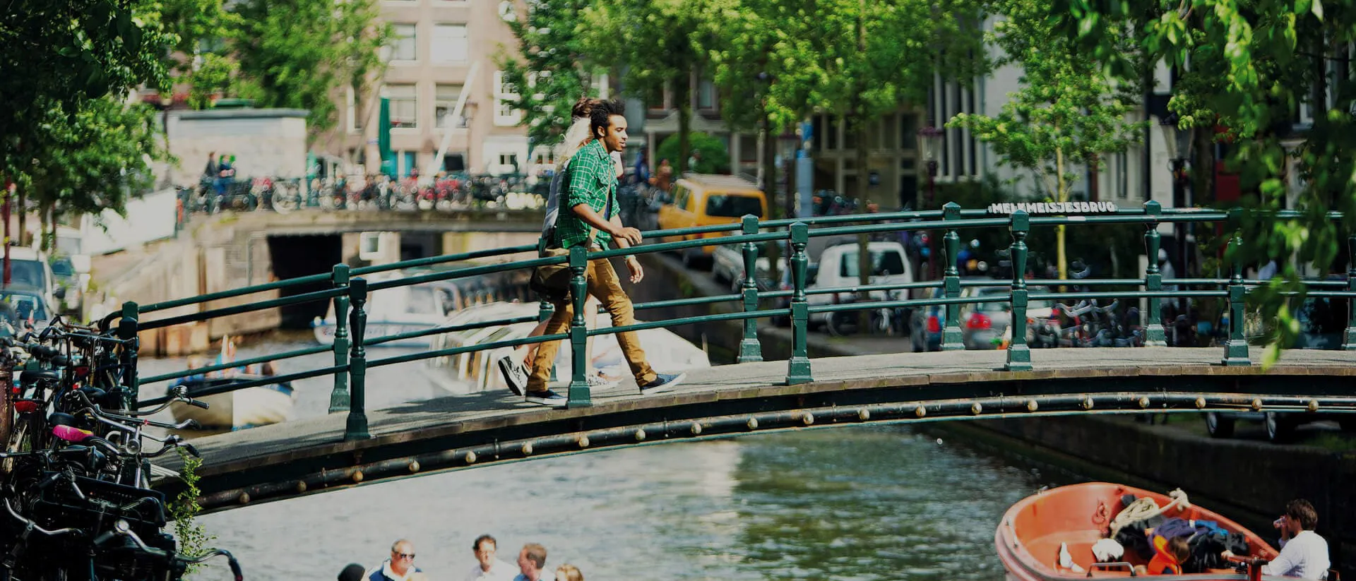 Boats on city canal and people on the bridge in Amsterdam, Netherlands