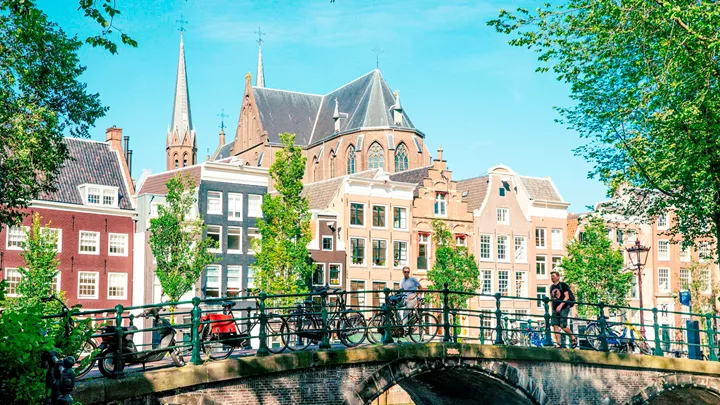 Traveller sat on a bike on a bridge in Amsterdam, Netherlands