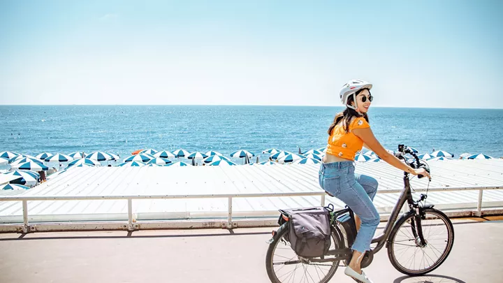 Traveller riding a bike along the beach in Nice, France