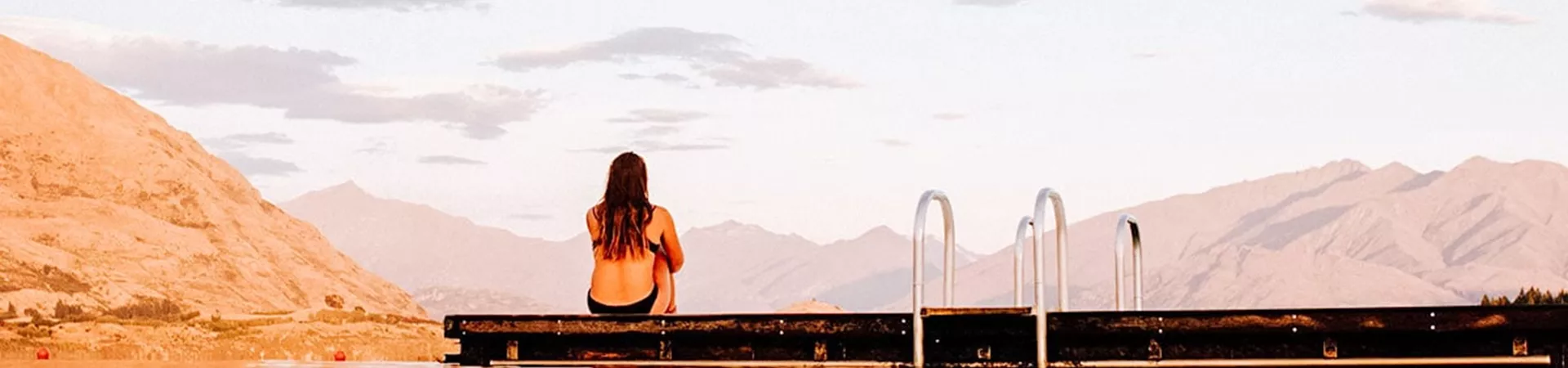 Girl sitting by the pool watching the mountains