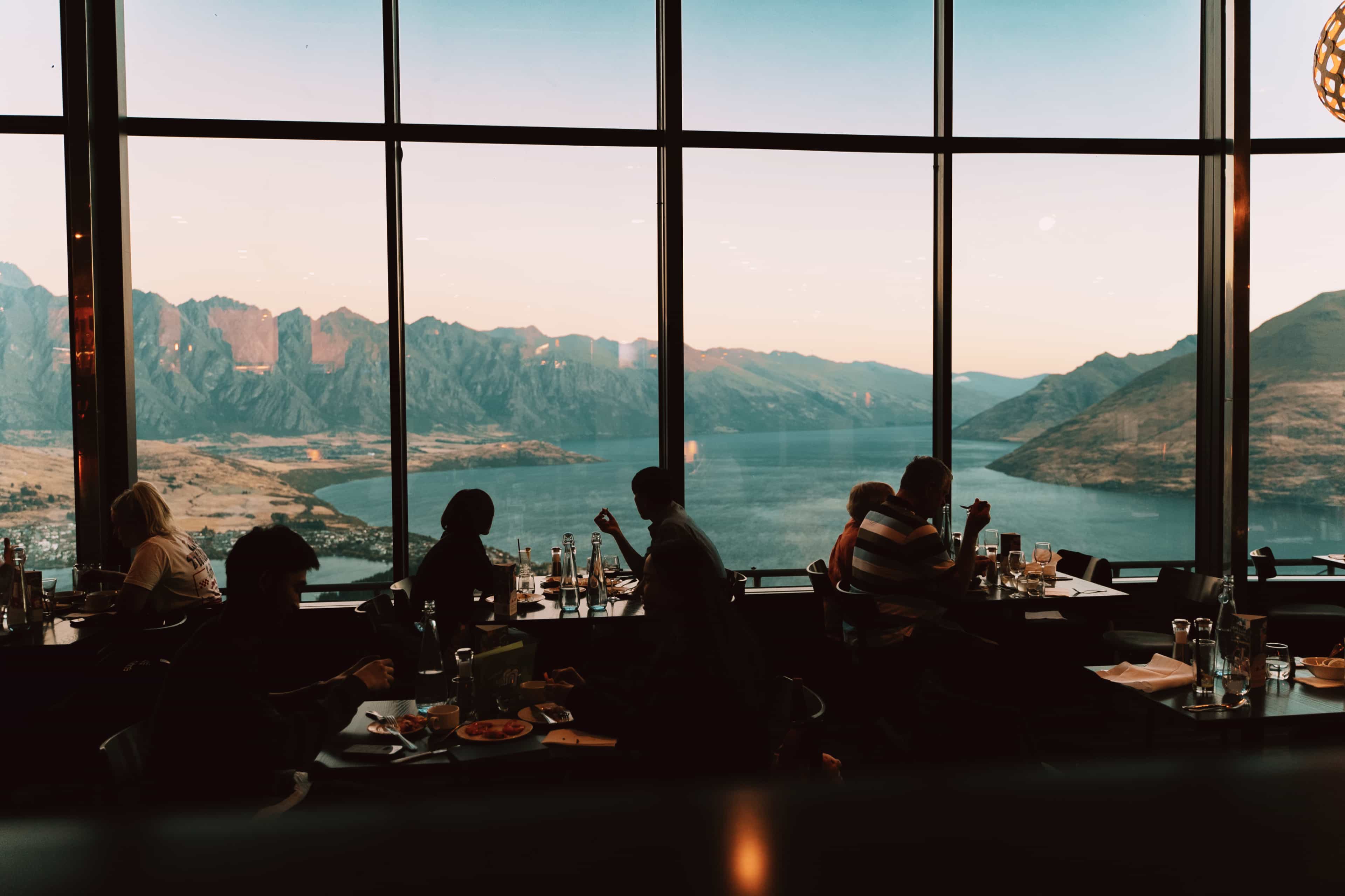 country-queenstown-whyvisit-diners-silhouetted-against-floor-to-ceiling-windows-enjoy-a-meal-overlooking-lake-wakatipu.jpg