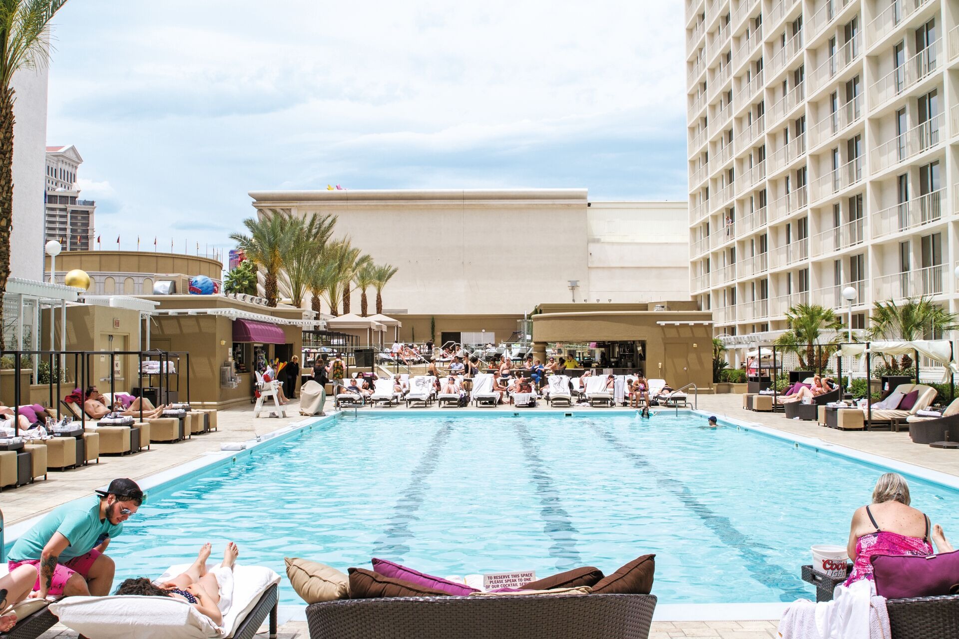 Hotel overlooking swimming pool with people sunbathing