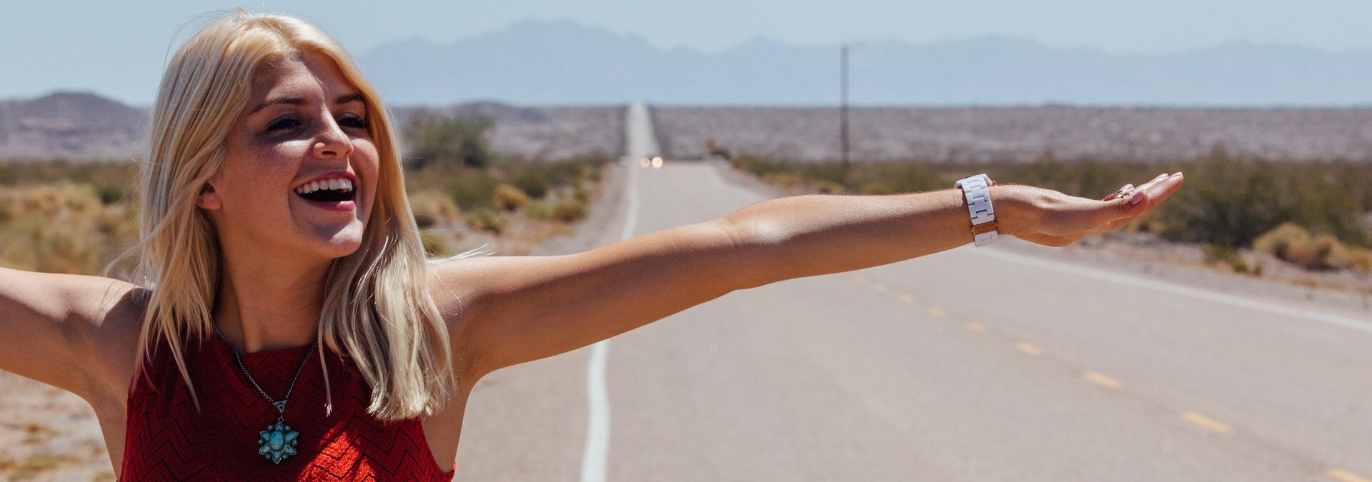 Smiling woman standing on the side of desert road in USA