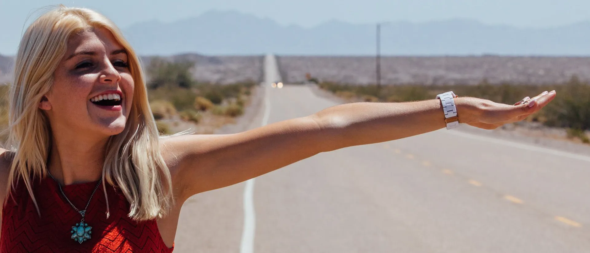Smiling woman standing on the side of desert road in USA