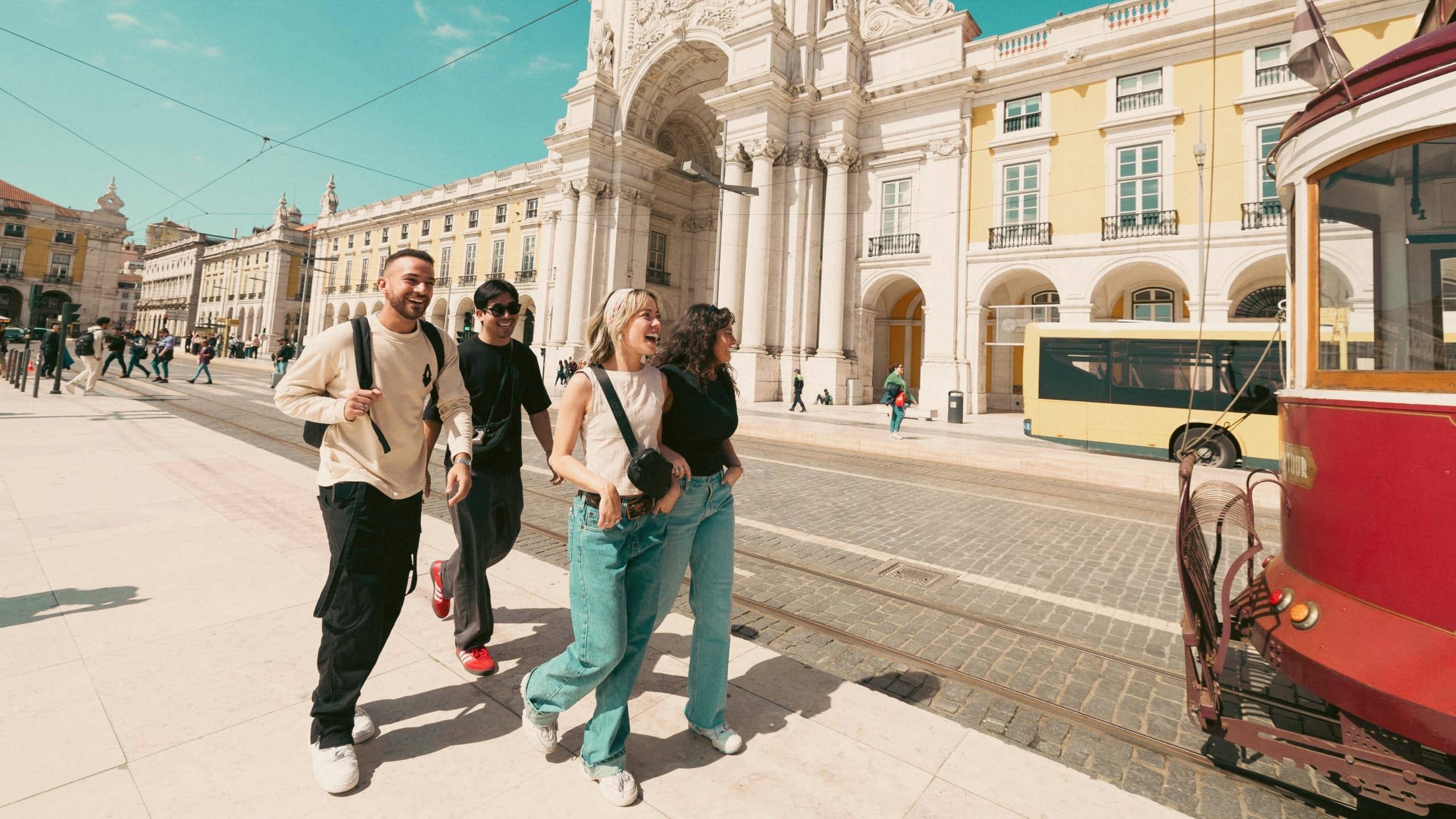 Contiki travellers exploring Lisbon’s Praça do Comércio beside the iconic yellow tram, discovering historic landmarks on the Spain & Portugal Panorama Tour
