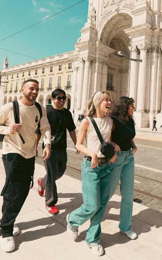 Contiki travellers exploring Lisbon’s Praça do Comércio beside the iconic yellow tram, discovering historic landmarks on the Spain & Portugal Panorama Tour