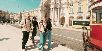 Contiki travellers exploring Lisbon’s Praça do Comércio beside the iconic yellow tram, discovering historic landmarks on the Spain & Portugal Panorama Tour