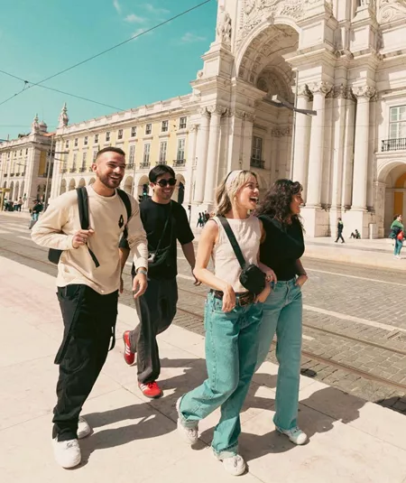 Contiki travellers exploring Lisbon’s Praça do Comércio beside the iconic yellow tram, discovering historic landmarks on the Spain & Portugal Panorama Tour