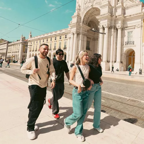 Contiki travellers exploring Lisbon’s Praça do Comércio beside the iconic yellow tram, discovering historic landmarks on the Spain & Portugal Panorama Tour