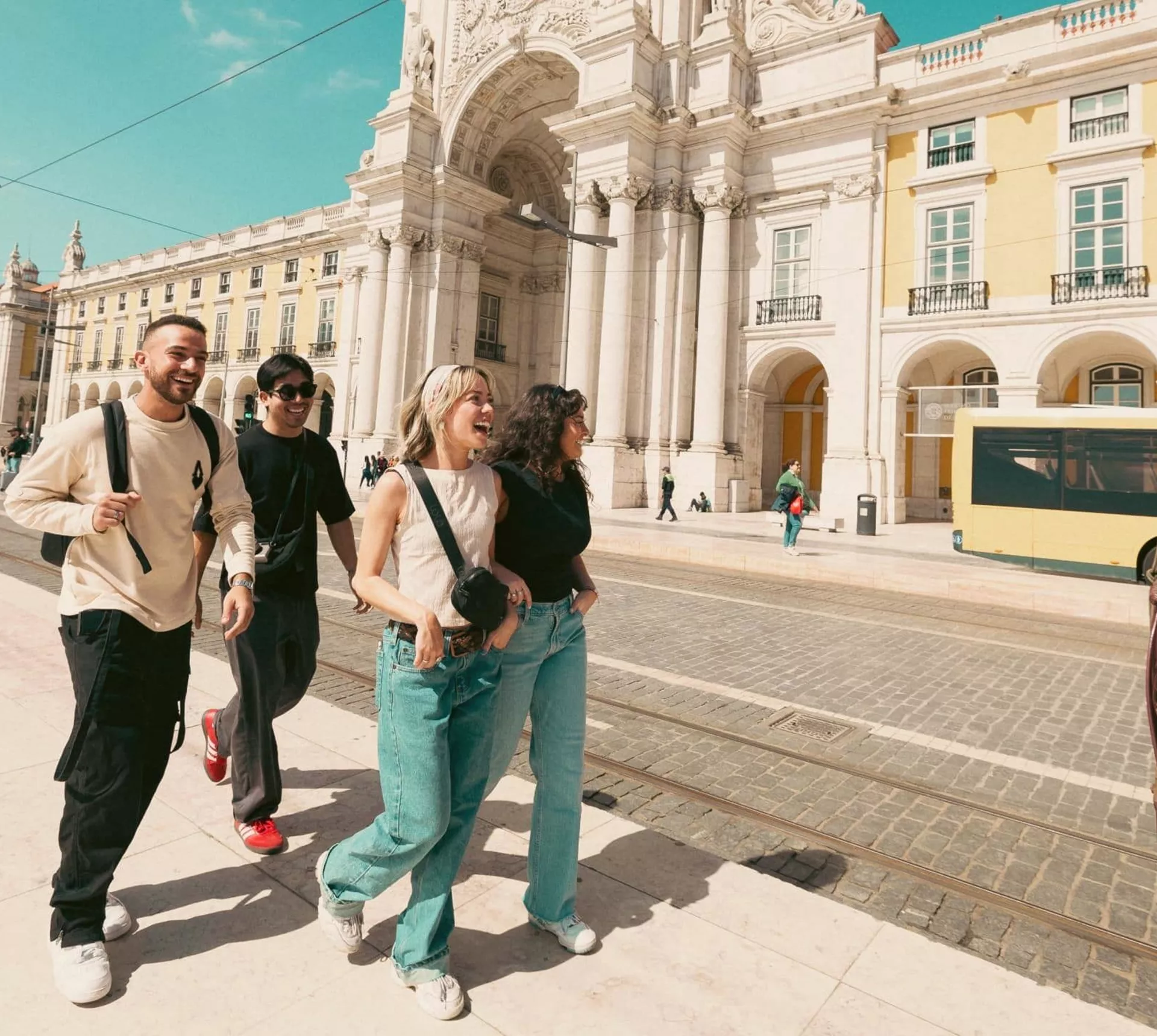 Contiki travellers exploring Lisbon’s Praça do Comércio beside the iconic yellow tram, discovering historic landmarks on the Spain & Portugal Panorama Tour