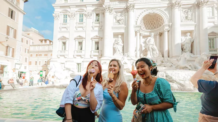 Three travellers enjoying gelato in front of the Trevi fountain, Rome, Italy