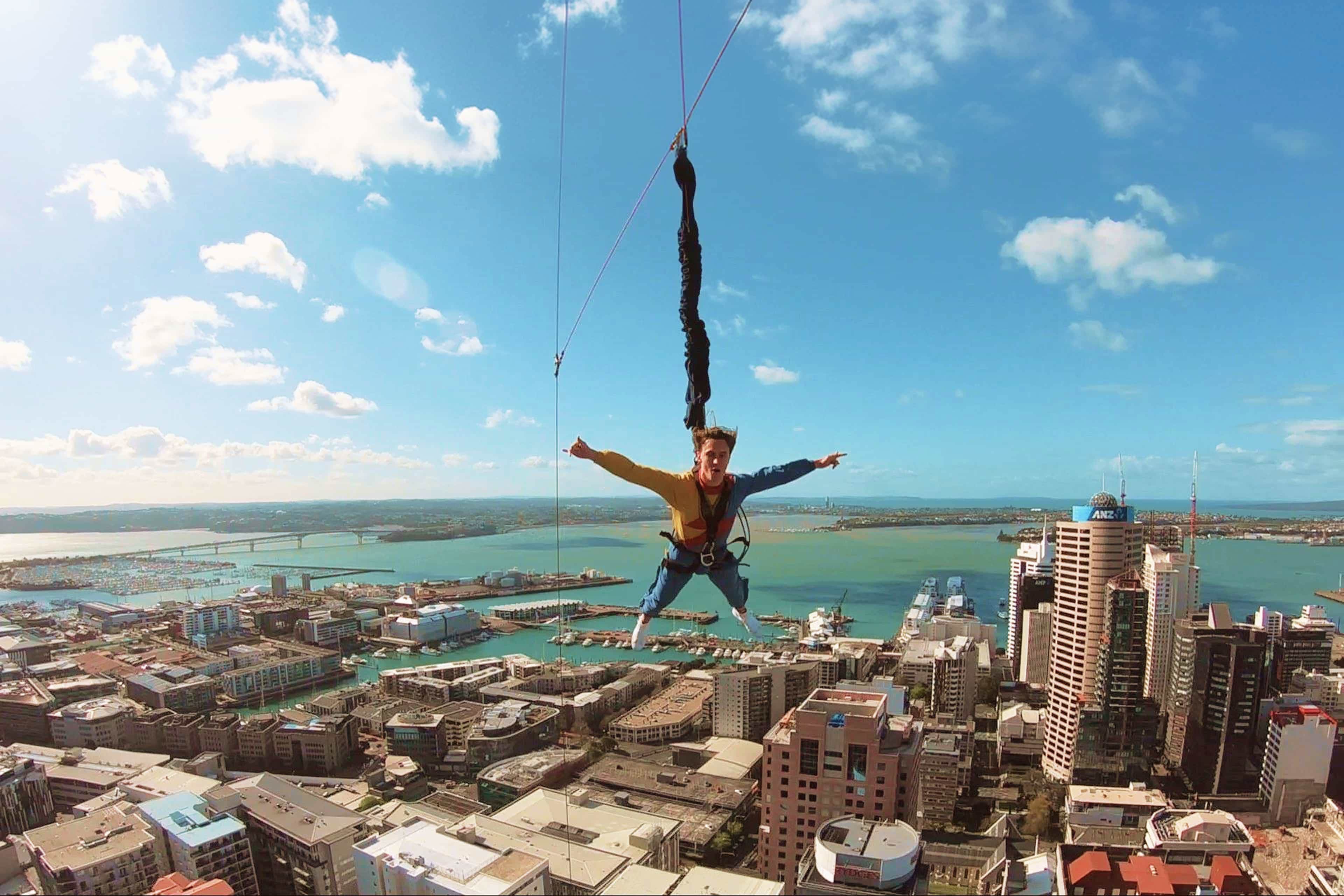 a-traveller-free-falls-from-the-sky-tower-on-the-skyjump-high-above-the-auckland-skyline-and-harbour-new-zealand.jpg