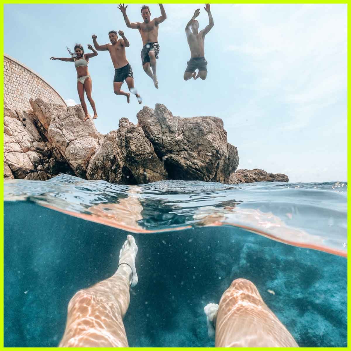 A group of friends jumps off a rocky cliff