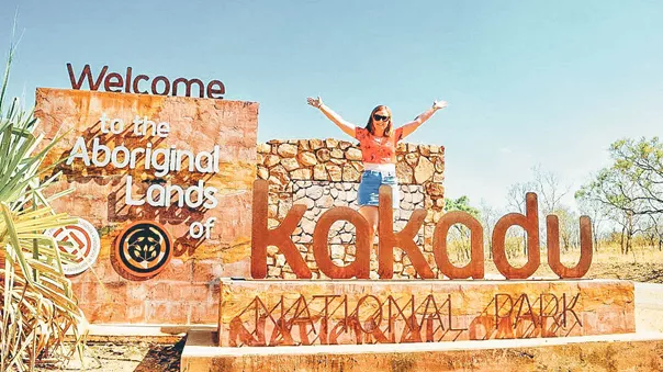 A woman posing for a photo with a Kakadu National Park sign