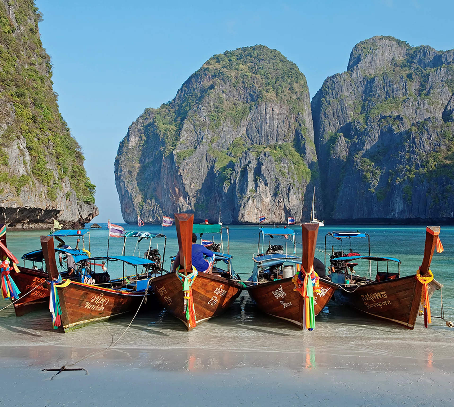 Four boats sitting on the edge of a beach in Thailand