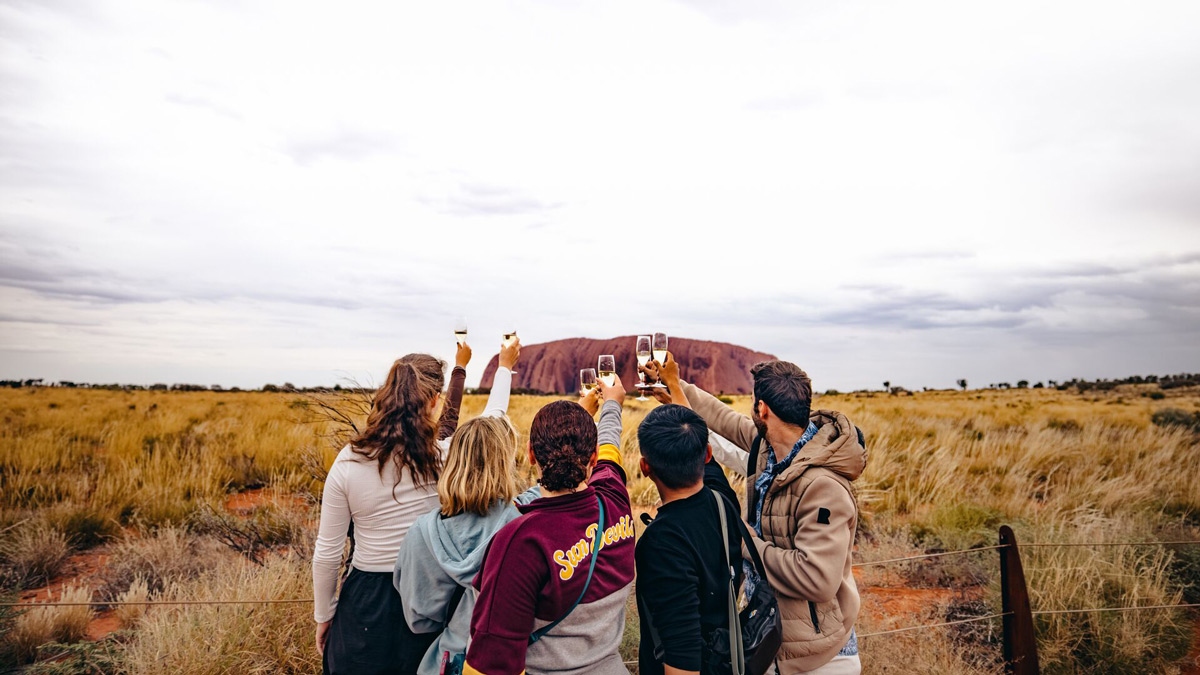 Group Of People Taking Photo Of Large Rocky Mountain