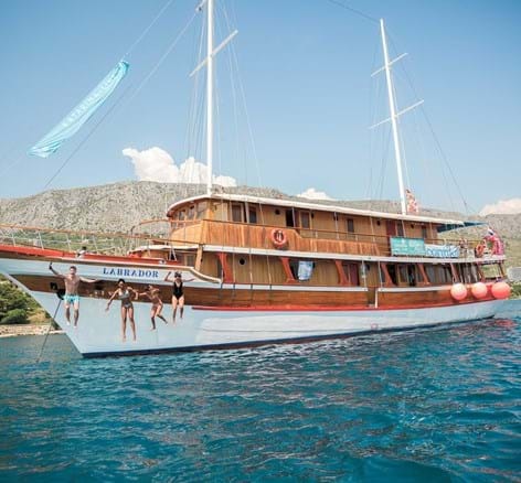 People jumping to the water from the big wooden boat