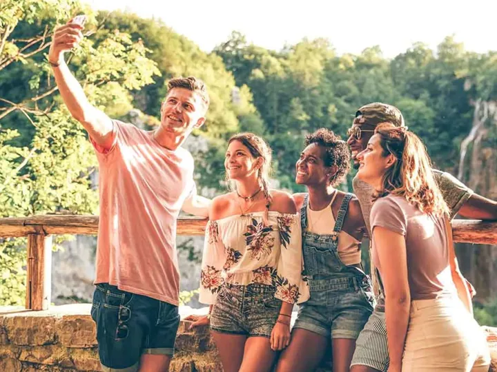 Group of young people taking selfie with a nature landscape at the background
