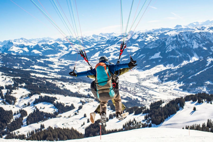 People skidiving with winter mountain view