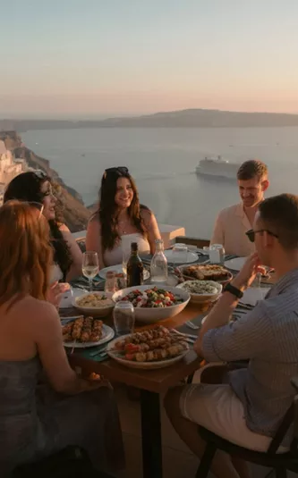 Contiki travellers gather for an evening meal overlooking Santorini's iconic whitewashed villages and sparkling Aegean Sea - Best of Greece Tour