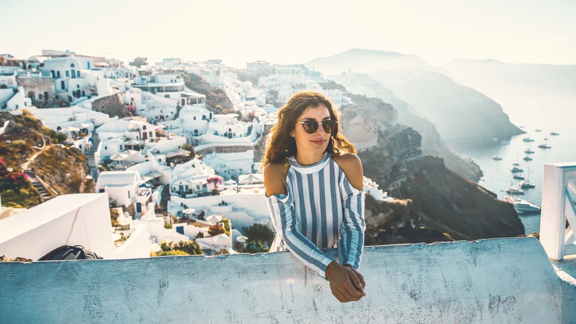 A Contiki traveller overlooks Santorini's whitewashed cliffside village and the Aegean Sea during the London to Santorini Trip