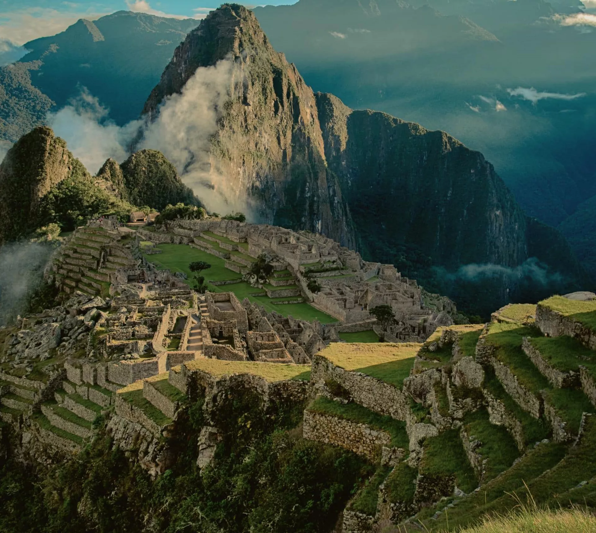 Panoramic aerial view of Machu Picchu ancient Inca citadel and terraces with cloud-covered Huayna Picchu mountain in the Sacred Valley Peru - Contiki Best of Peru Tour