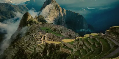 Panoramic aerial view of Machu Picchu ancient Inca citadel and terraces with cloud-covered Huayna Picchu mountain in the Sacred Valley Peru - Contiki Best of Peru Tour