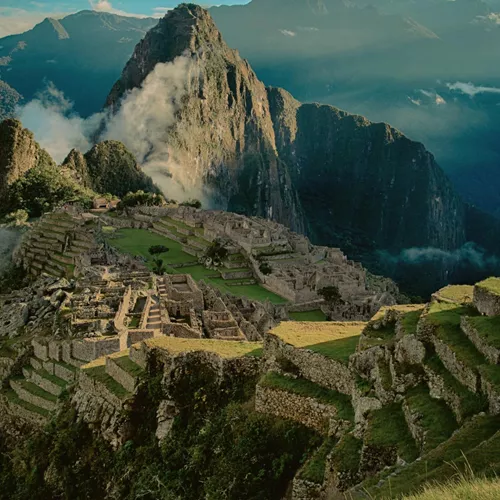 Panoramic aerial view of Machu Picchu ancient Inca citadel and terraces with cloud-covered Huayna Picchu mountain in the Sacred Valley Peru - Contiki Best of Peru Tour