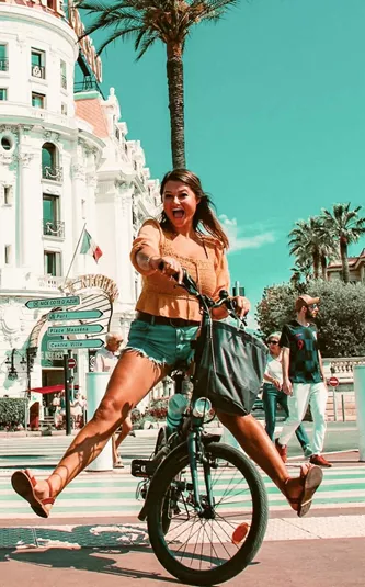 Traveller rides a bicycle through Nice, France, on the Contiki Barcelona to Rome Quest Summer Tour