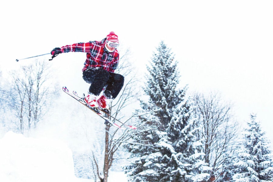Skier doing ski tricks with winter forest landscape in the background