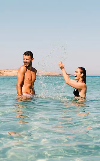 Two young travellers laughing and splashing in crystal clear turquoise waters off the Spanish coast - Contiki Ibiza & Mallorca Island Hopping Tour