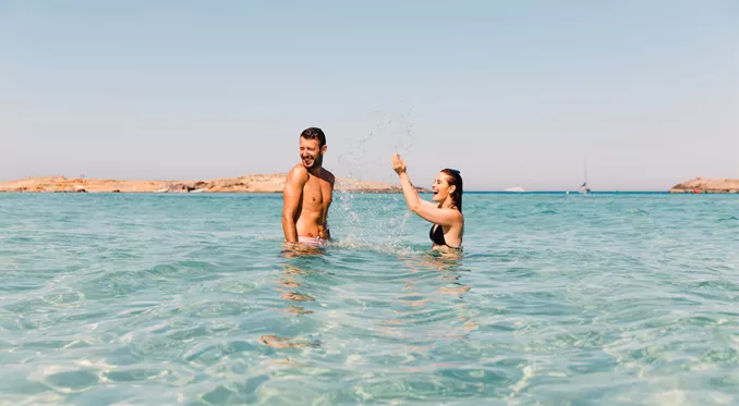 Two young travellers laughing and splashing in crystal clear turquoise waters off the Spanish coast - Contiki Ibiza & Mallorca Island Hopping Tour