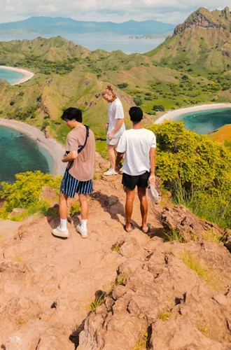 Young travellers on the rocky summit of Padar Island overlooking the iconic tri-bay coastline of Komodo National Park Indonesia - Contiki Indonesia Island Hopping Tour