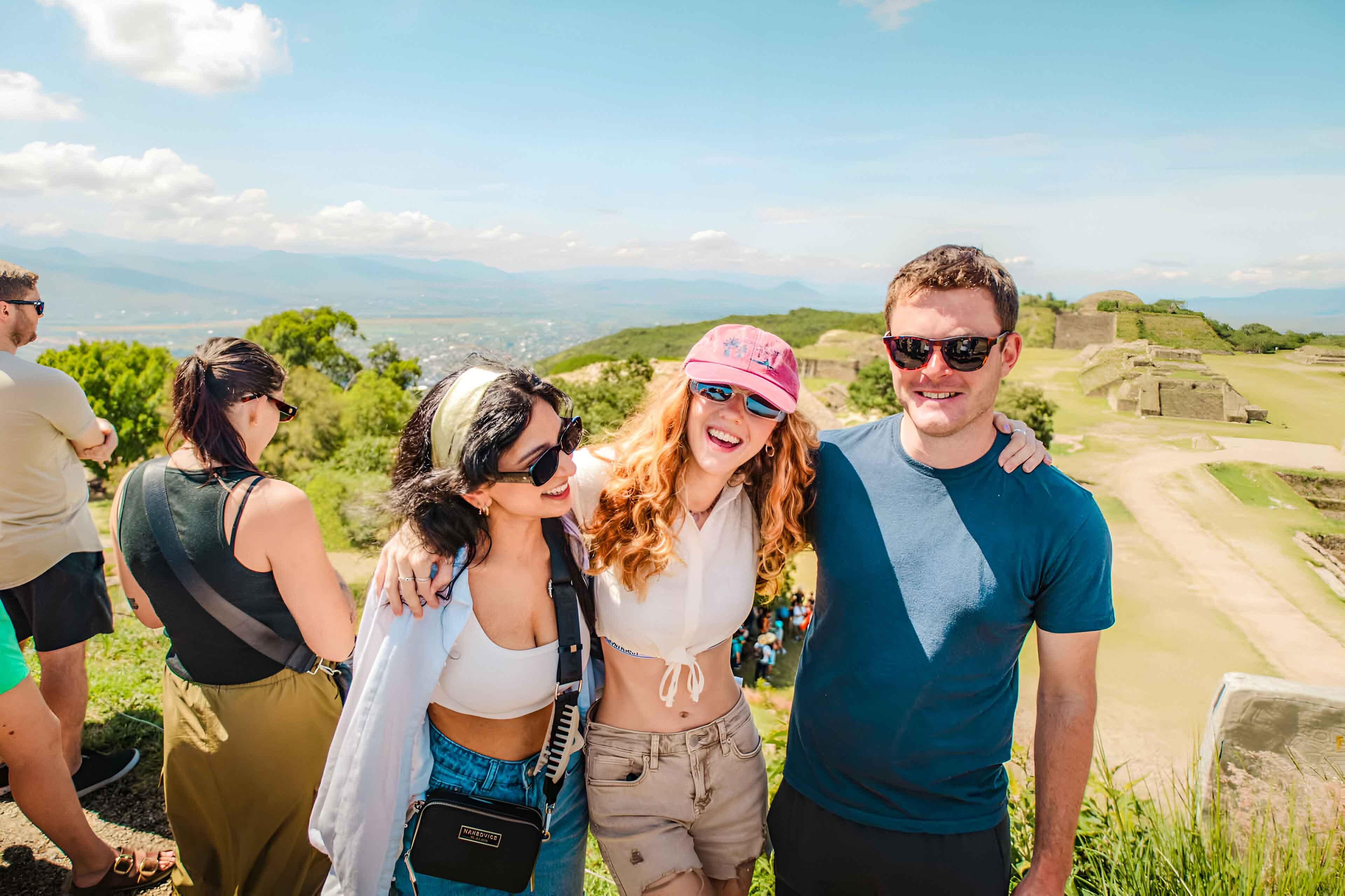 Three friends smiling with a mexico landmark at the background