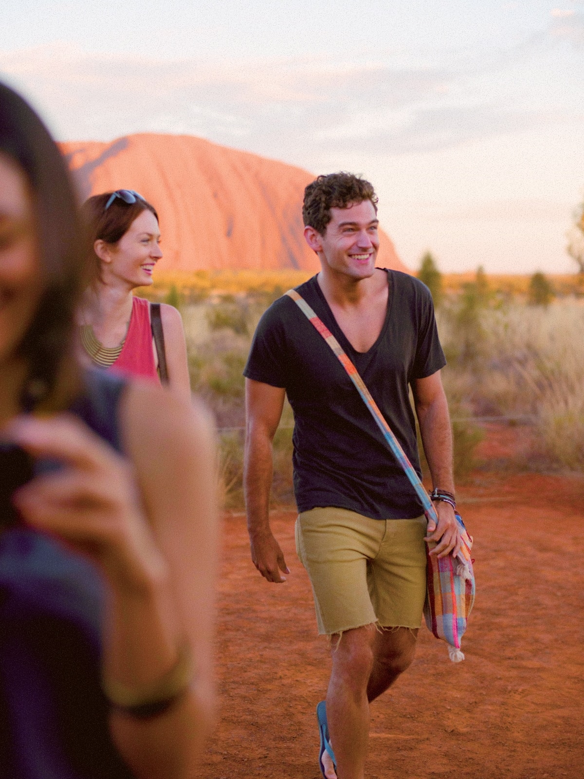 Travellers walking at sunset with Uluru in the background, Northern Territory, Australia.