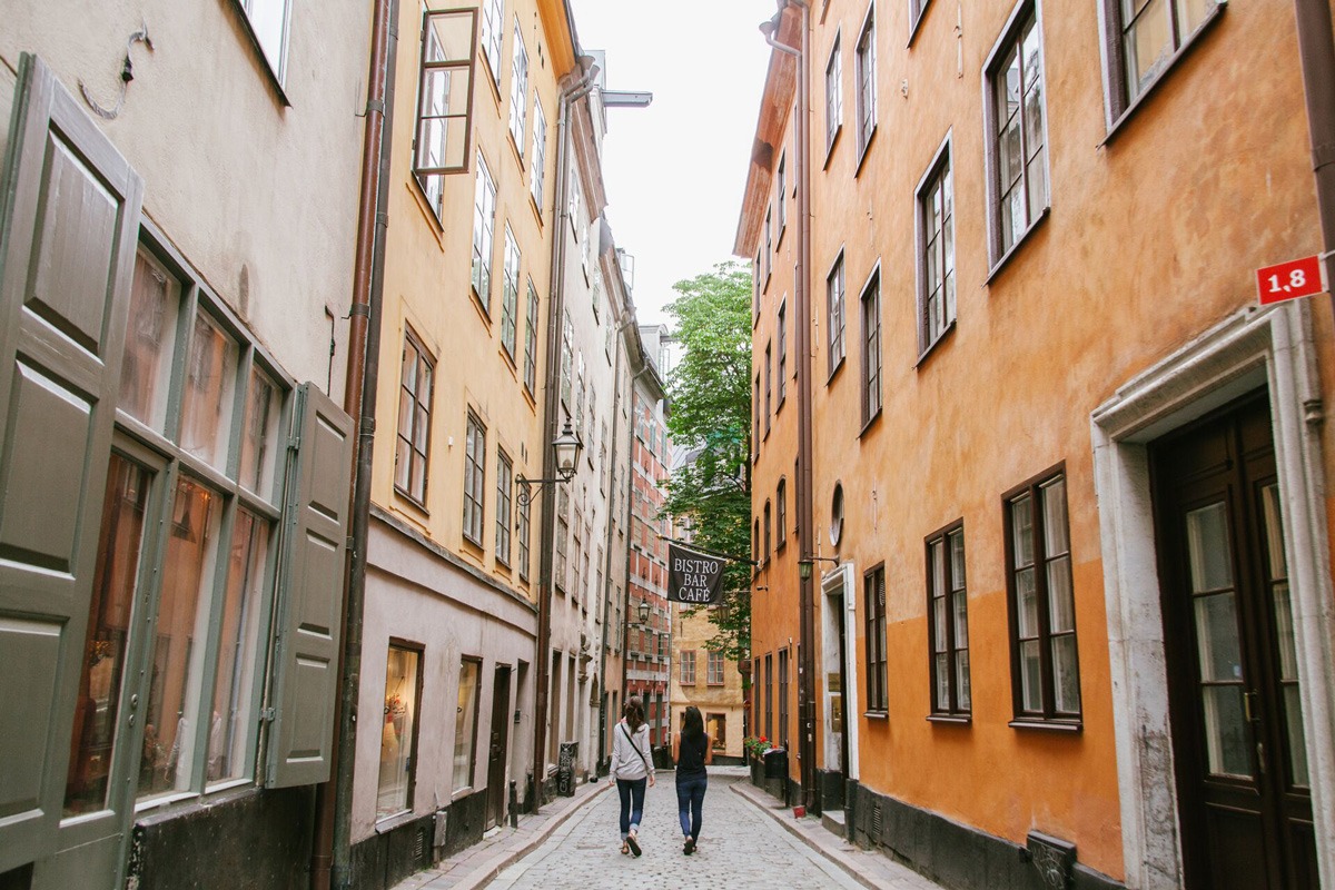 Two friends walking in a narrow city street in Sweden.