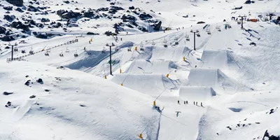 Aerial view of skiers and snowboarders on the ski runs with chairlifts and snow jumps n New Zealand - Contiki Ski NZ Tour