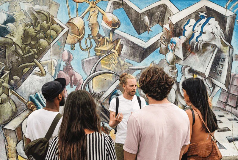 a group of tourists at the East Side Gallery, a section of the Berlin Wall