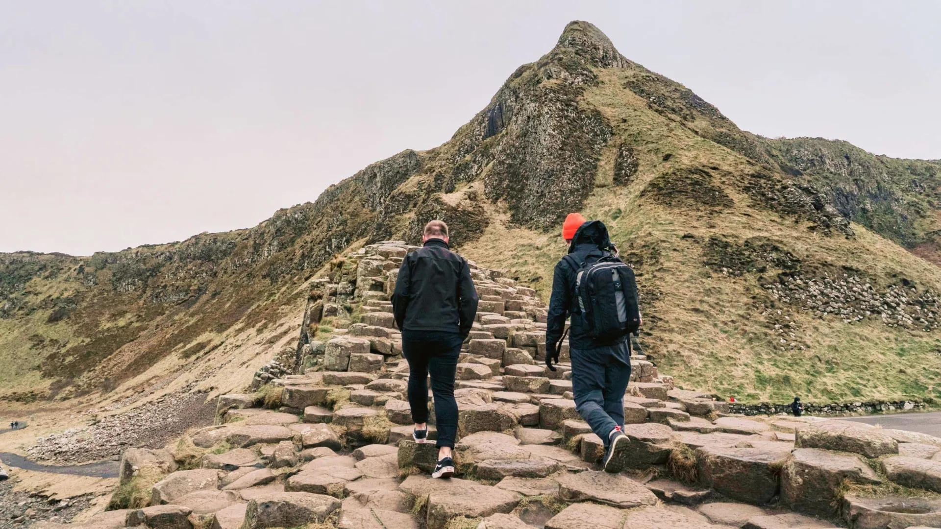 Travellers walking across the Giant's Causeway basalt columns in County Antrim, Northern Ireland, on the Contiki Ireland in a Week 35 to 45 Tour