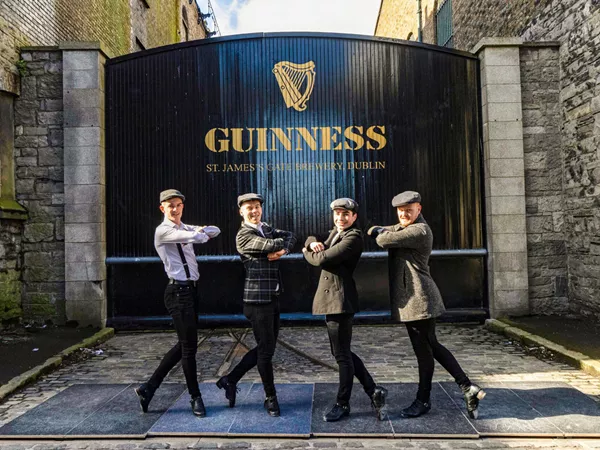 Four People Standing In Front Of Guinness Brewery Big Gate