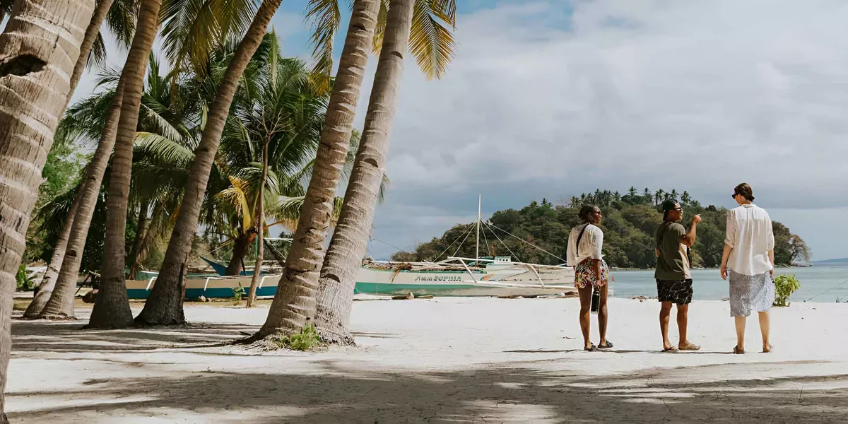 Three People Talking While Walking On The Beach