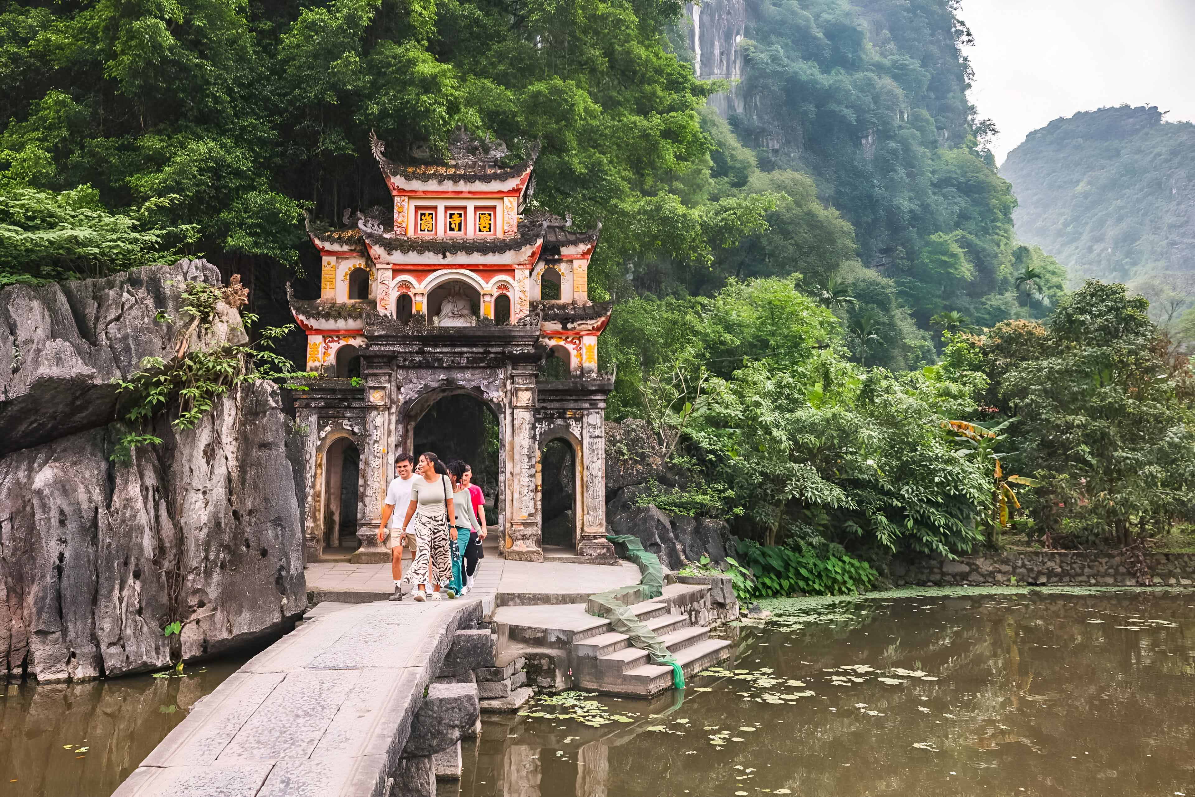 Group Of Young People Walking Close To Temple Gates in Vietnam.